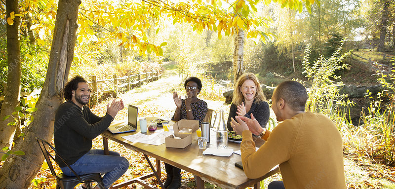 Happy business people clapping and meeting in autumn park